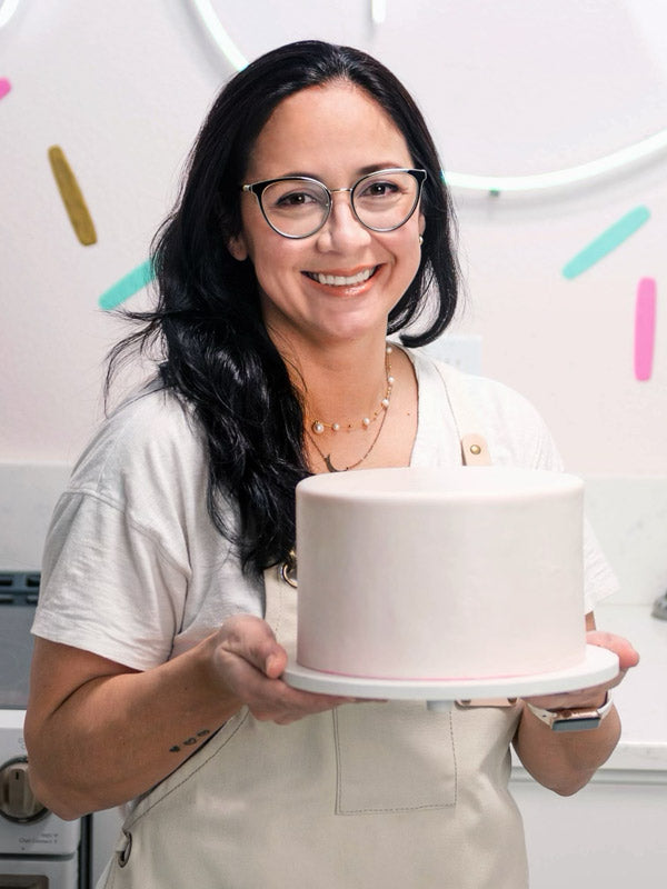 Elizabeth Marek holding a white cake covered by flawless fondant